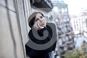 Young beautiful woman thinking and feeling sad suffering depression at urban city background home balcony