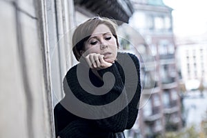 Young beautiful woman thinking and feeling sad suffering depression at urban city background home balcony