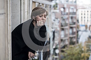 Young beautiful woman thinking and feeling sad suffering depression at urban city background home balcony