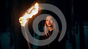 Young beautiful woman with torch in night forest