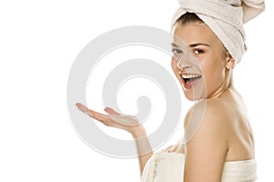 Young beautiful woman with towel on her head holding imaginary object on her hand