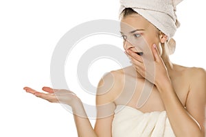 Young beautiful woman with towel on her head holding imaginary object on her hand