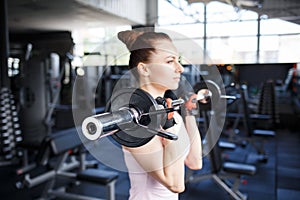 Young beautiful woman training biceps with barbell