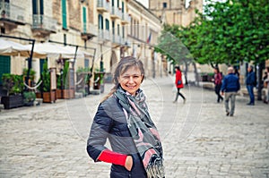 Young beautiful woman traveler with black jacket looking at camera, smile and posing in Matera city historical centre