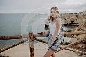 Young beautiful woman traveler looking at sunset and beautiful seascape with a lookout point. Freedom, travel, vacation