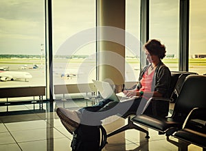 Young beautiful woman traveler sits at the airport with a laptop