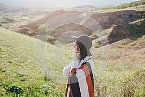 Young beautiful woman traveler wearing hat and poncho relaxing on the top of the hill