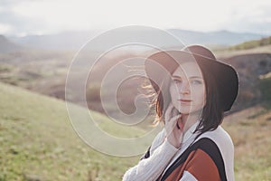 Young beautiful woman traveler wearing hat and poncho relaxing on the top of the hill