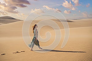 Young beautiful woman traveling in the desert. Sandy dunes and blue sky on sunny summer day. Travel, adventure, freedom