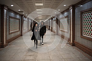 A young beautiful woman tries to escape from a robber in black clothes . in the underpass. at night