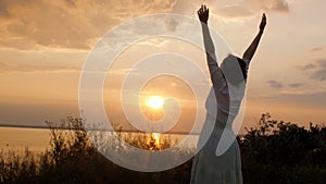 Young beautiful woman turning to God in nature, the girl praying folded her hands at the chin, concept of religion