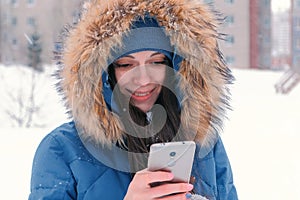 Young beautiful woman typing a message on her mobile phone, then looking at camera and smiling.