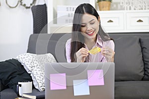 Young beautiful woman is using credit card for online shopping on internet website at home, e-commerce concept