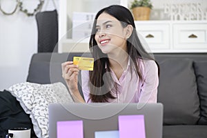 Young beautiful woman is using credit card for online shopping on internet website at home, e-commerce concept