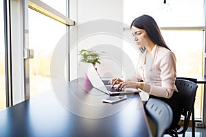 Young beautiful woman using her laptop while sitting in chair at her working place