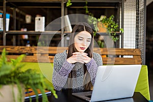 Young beautiful woman using her laptop while sitting in chair at her working place