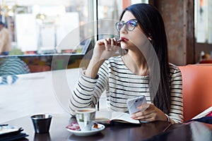 Young beautiful woman using her mobile phone in coffee.