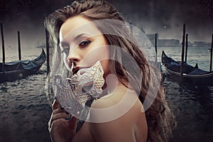 Beautiful brunette with Venetian mask. Young and beautiful woman on Venetian view background, gondolas.