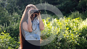Young beautiful woman with very long hair looks through binoculars.