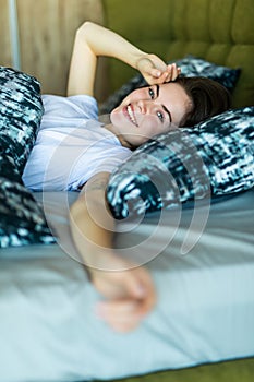 Young beautiful, woman waking up fully rested in bed
