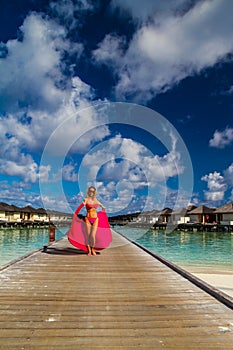 Young beautiful woman walking on a jetty, tropical vacation