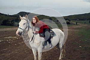 Young beautiful woman walking in the mountains with her horse