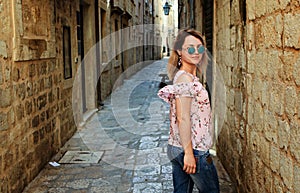 Young beautiful woman walking in old city street, summer Europe vacation, travel, fun, happy, smiling, sunglasses.