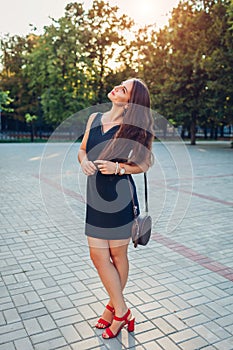 Young beautiful woman walking in summer park. Stylish lady wearing fashionable outfit