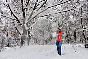 Young beautiful woman walks in the winter in the snow-covered fairy-tale forest near the branchy perennial old oak