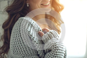 Young beautiful woman in warm knitted clothes at home. Female indoor portrait.