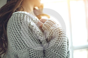 Young beautiful woman in warm knitted clothes at home. Female indoor portrait.