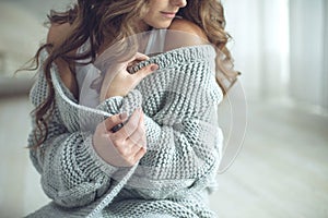 Young beautiful woman in warm knitted clothes at home. Female indoor portrait.