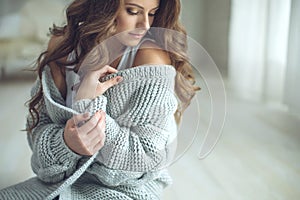 Young beautiful woman in warm knitted clothes at home. Female indoor portrait.