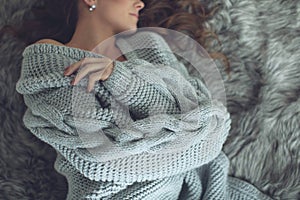 Young beautiful woman in warm knitted clothes at home. Female indoor portrait.