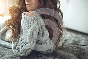 Young beautiful woman in warm knitted clothes at home. Female indoor portrait.