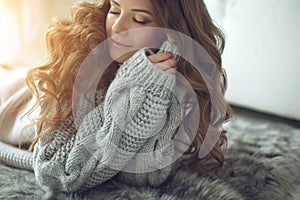 Young beautiful woman in warm knitted clothes at home. Female indoor portrait.