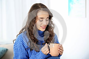 Young beautiful woman in warm sweater with cup of hot drink