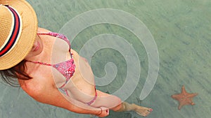 Young beautiful woman watching a starfish in playa Estrella, Panama photo