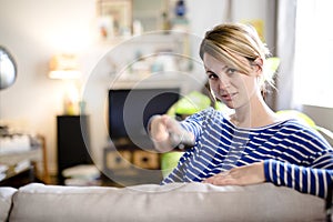 Young beautiful woman watching TV on a sofa at home