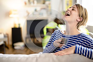 Young beautiful woman watching TV on a sofa at home