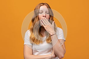 Young beautiful woman with wavy redhead bored yawning tired covering mouth with hand. Restless and sleepiness photo