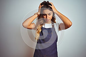 Young beautiful woman wearing apron over grey isolated background suffering from headache desperate and stressed because pain and