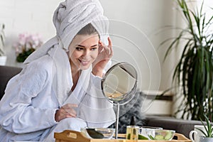 Young beautiful woman wearing a bathrobe at home. doing her daily skincare routine with natural cosmetics