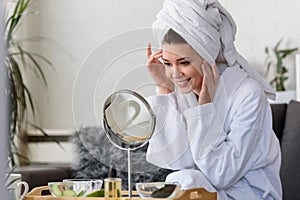Young beautiful woman wearing a bathrobe at home. doing her daily skincare routine with natural cosmetics