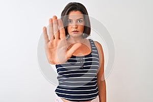 Young beautiful woman wearing blue striped t-shirt standing over isolated white background doing stop sing with palm of the hand