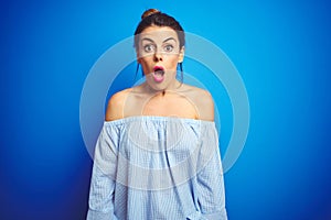 Young beautiful woman wearing bun hairstyle over blue isolated background In shock face, looking skeptical and sarcastic,