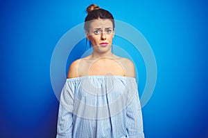 Young beautiful woman wearing bun hairstyle over blue isolated background skeptic and nervous, frowning upset because of problem