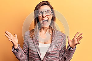 Young beautiful woman wearing business clothes and glasses crazy and mad shouting and yelling with aggressive expression and arms