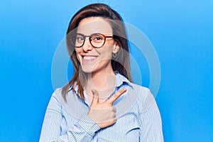 Young beautiful woman wearing business clothes and glasses smiling cheerful pointing with hand and finger up to the side