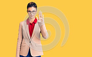 Young beautiful woman wearing business shirt and glasses doing stop sing with palm of the hand